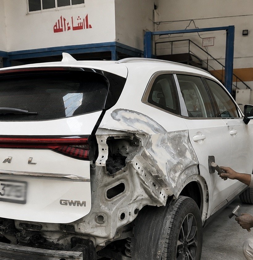 Damaged rear quarter panel of a white SUV being assessed for body repair