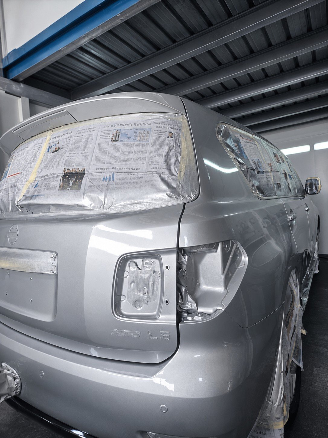 Silver vehicle masked and prepared for exterior paintwork in the workshop