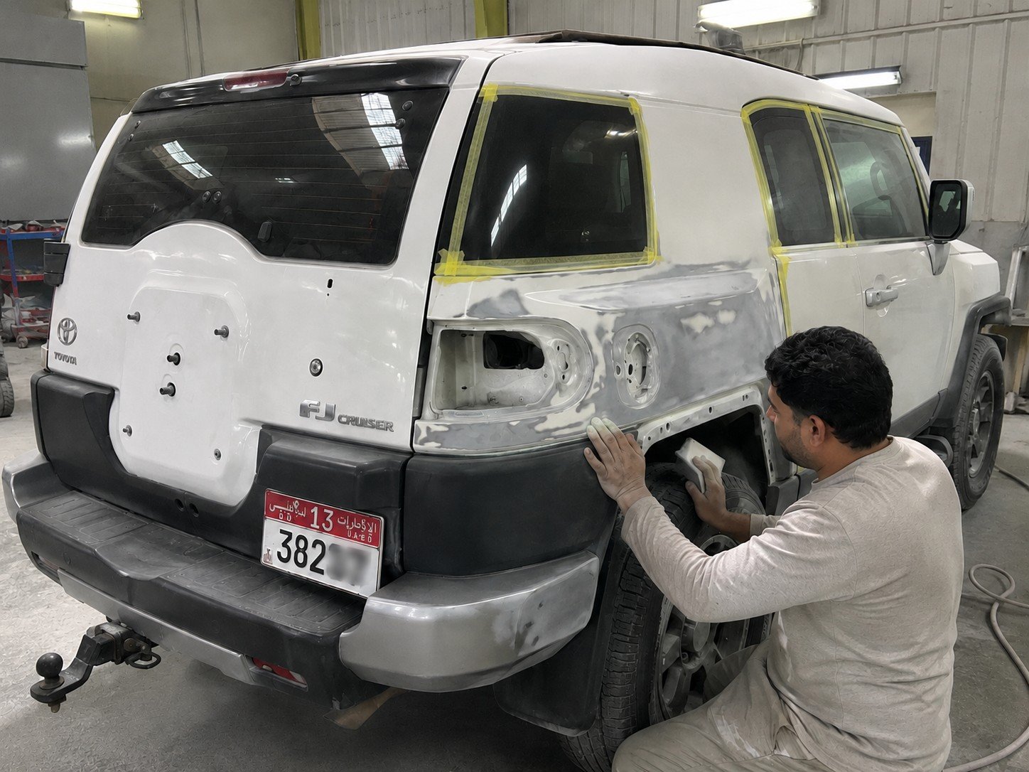 Technician preparing a rear body panel on a white SUV at Paintora